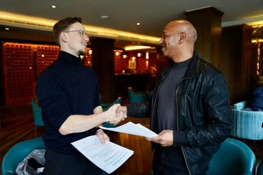 Prabin Thapa sharing a laugh with Linus at a table.